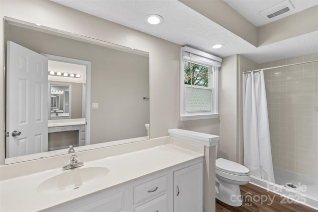 bathroom featuring toilet, a stall shower, a textured ceiling, and visible vents