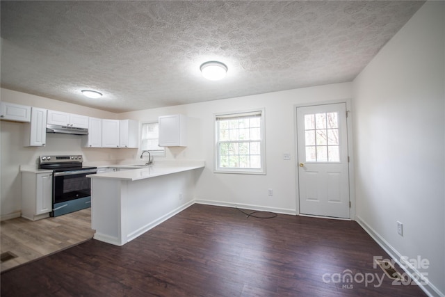 kitchen with electric stove, light countertops, a sink, a peninsula, and under cabinet range hood