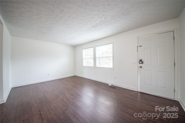 interior space with a textured ceiling, baseboards, and dark wood-style flooring