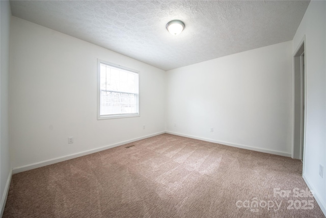 carpeted spare room with baseboards and a textured ceiling