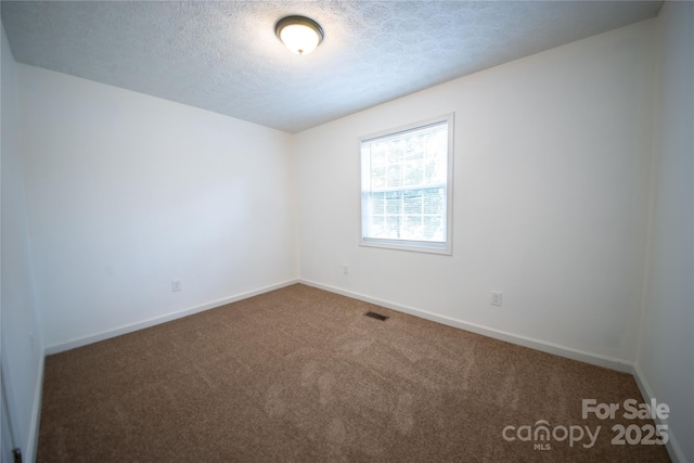 spare room featuring carpet floors, baseboards, visible vents, and a textured ceiling