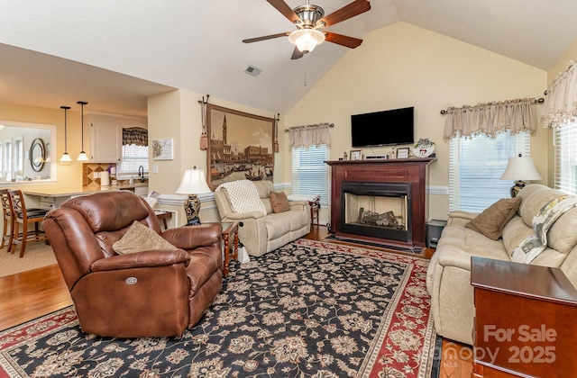 living area with a fireplace, plenty of natural light, wood finished floors, and visible vents