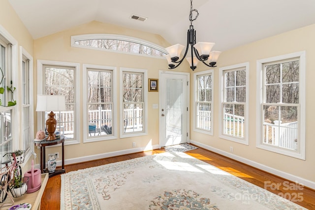 interior space with visible vents, vaulted ceiling, wood finished floors, and a chandelier