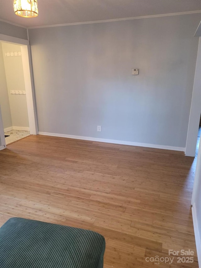 spare room featuring ornamental molding, wood finished floors, and baseboards