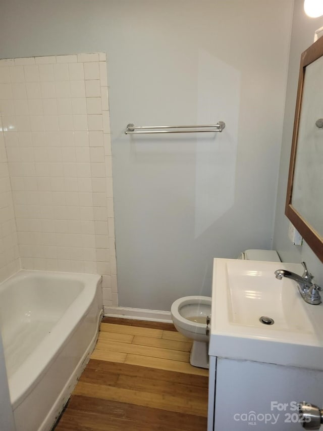 bathroom with vanity, wood finished floors, toilet, and baseboards