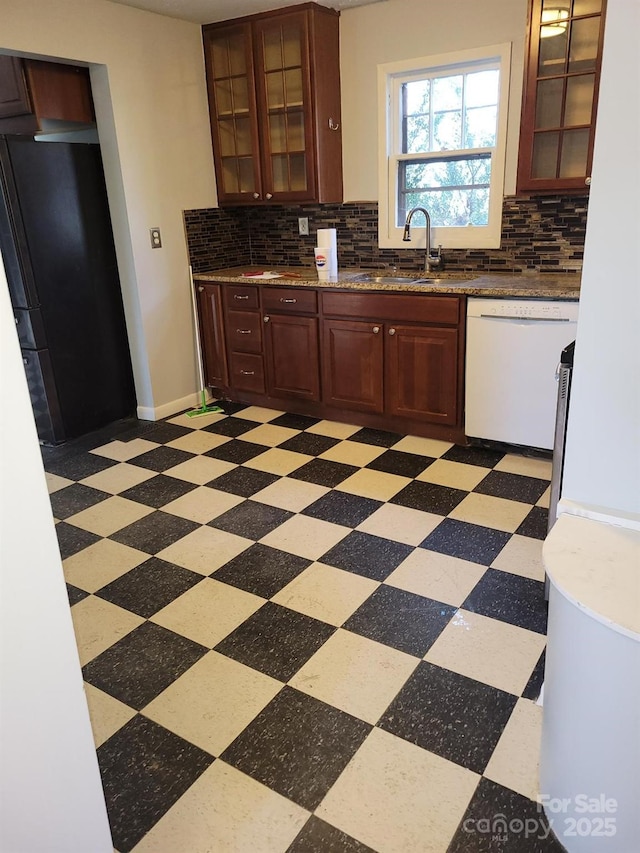 kitchen with white dishwasher, a sink, freestanding refrigerator, decorative backsplash, and light floors