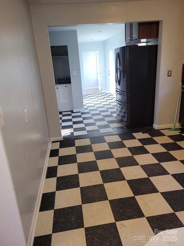 hallway featuring baseboards, dark floors, and washer / clothes dryer