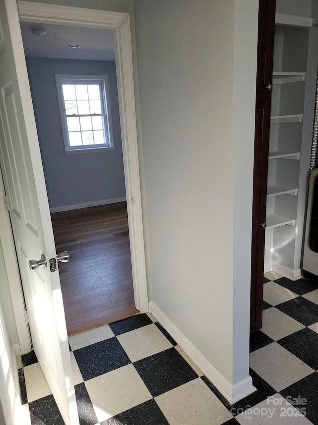 hall with baseboards and tile patterned floors