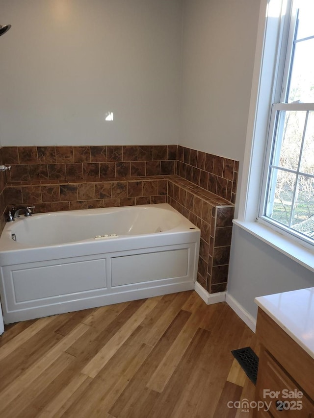 bathroom with a bath, tile walls, visible vents, and wood finished floors