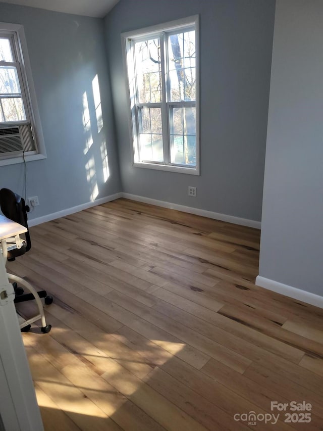 empty room with cooling unit, baseboards, and wood finished floors