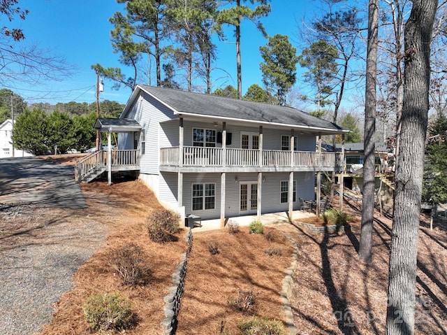 rear view of property featuring driveway, a patio area, a deck, and french doors