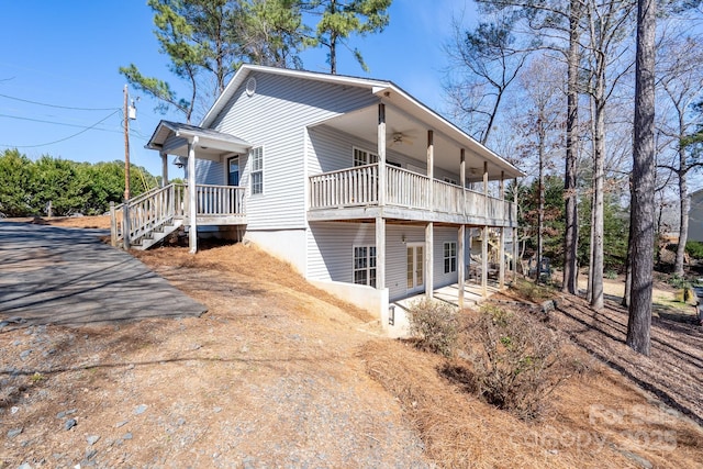 view of side of home with ceiling fan and dirt driveway