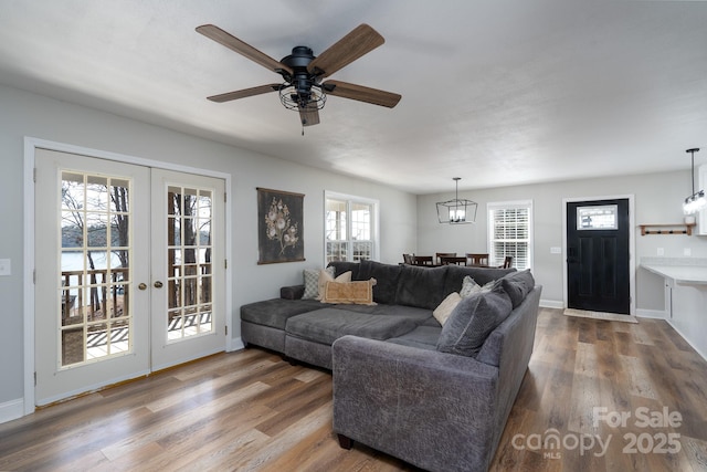 living area featuring ceiling fan, baseboards, wood finished floors, and french doors