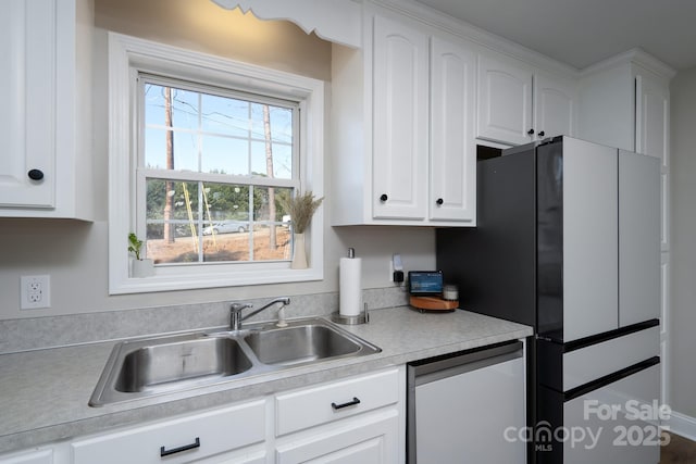 kitchen featuring white cabinets, light countertops, a sink, and dishwashing machine