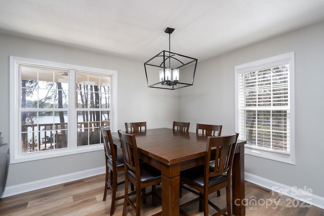 dining area with an inviting chandelier, wood finished floors, visible vents, and baseboards