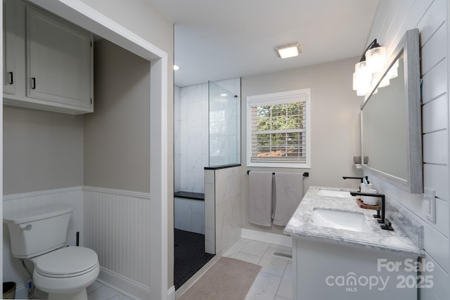 full bath with a wainscoted wall, marble finish floor, walk in shower, and a sink