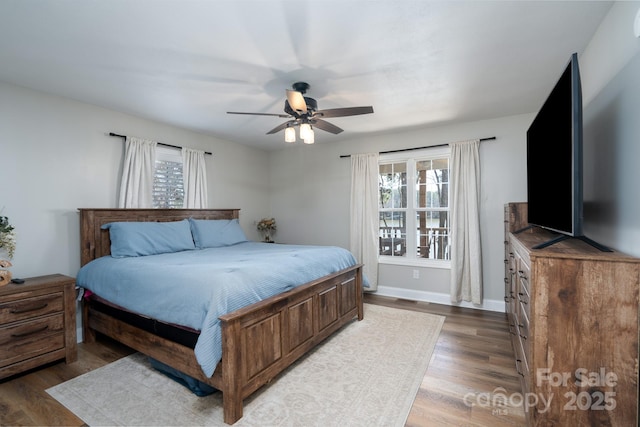 bedroom with multiple windows, wood finished floors, and baseboards