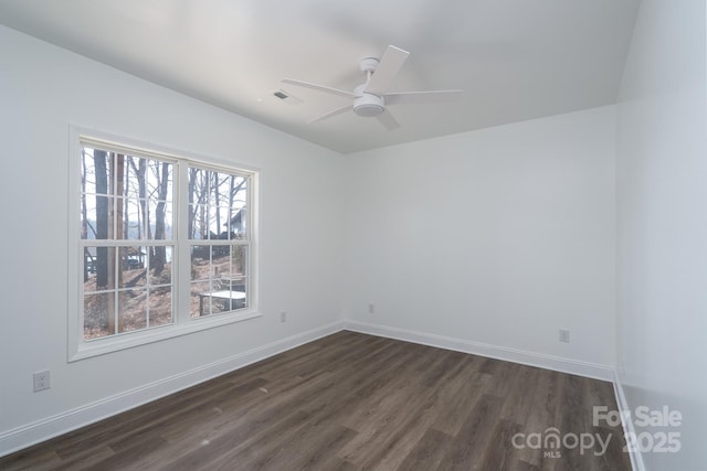 spare room featuring a ceiling fan, visible vents, baseboards, and dark wood-style flooring