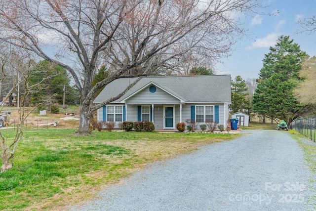 view of front facade featuring driveway, a front yard, a storage unit, and an outdoor structure