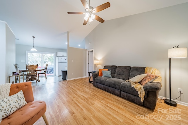 living room featuring high vaulted ceiling, light wood finished floors, a ceiling fan, and baseboards