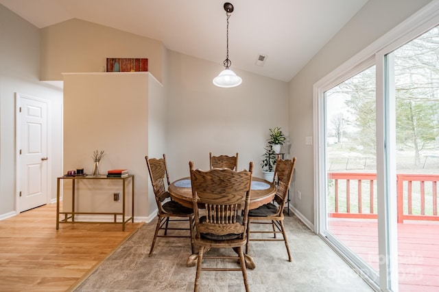 dining area with lofted ceiling, light wood-style floors, baseboards, and visible vents