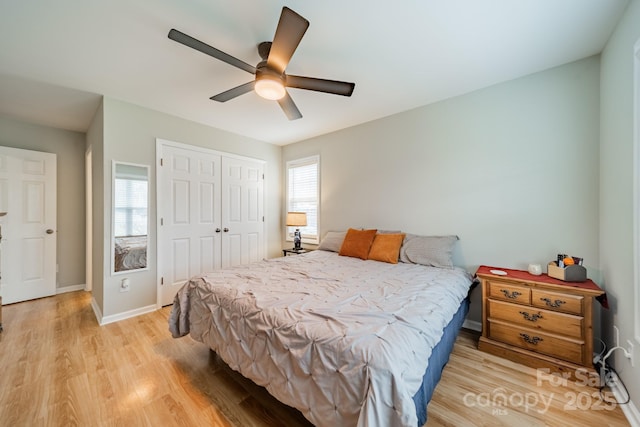 bedroom featuring light wood-type flooring, ceiling fan, baseboards, and a closet