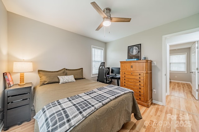 bedroom with light wood-style floors, multiple windows, and baseboards