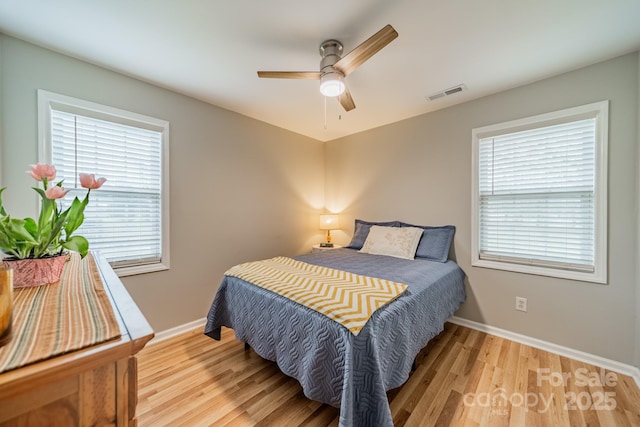 bedroom featuring light wood-style floors, baseboards, visible vents, and ceiling fan