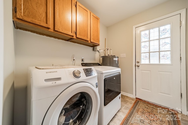 washroom with baseboards, cabinet space, washing machine and clothes dryer, and electric water heater