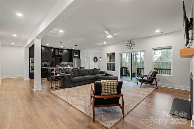 living room with light wood finished floors, recessed lighting, baseboards, and ceiling fan