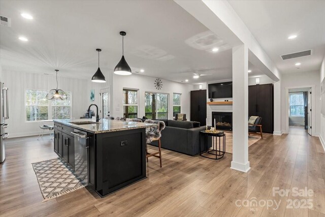 kitchen featuring visible vents, a breakfast bar, light wood-style flooring, appliances with stainless steel finishes, and dark cabinetry