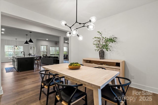 dining area featuring a chandelier, baseboards, and dark wood finished floors