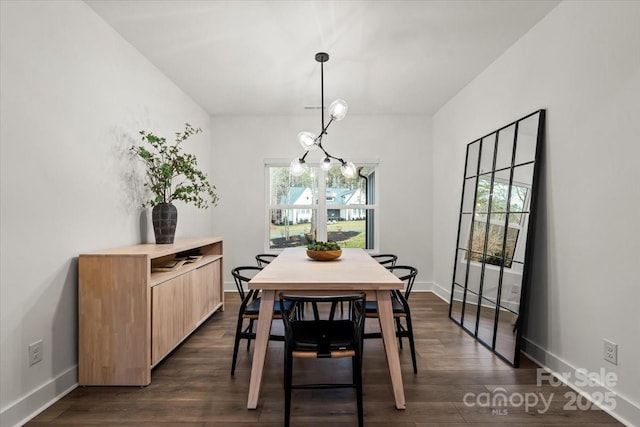 dining room featuring dark wood finished floors, an inviting chandelier, and baseboards