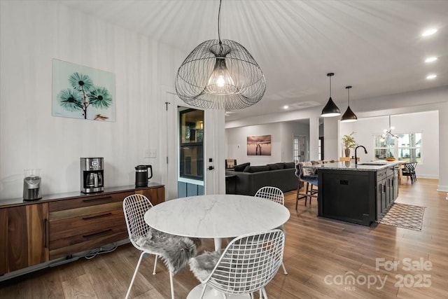 dining space with a notable chandelier, wood finished floors, and recessed lighting