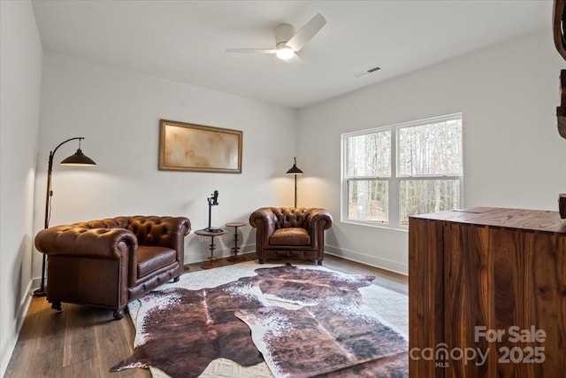 sitting room featuring visible vents, baseboards, a ceiling fan, and dark wood-style flooring