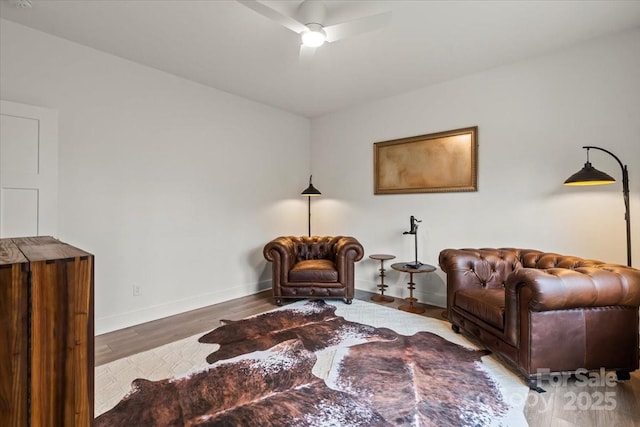 living area featuring ceiling fan, baseboards, and wood finished floors