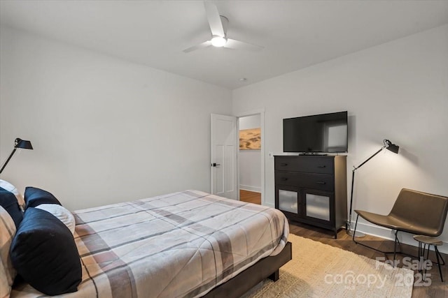 bedroom with a ceiling fan, wood finished floors, and baseboards