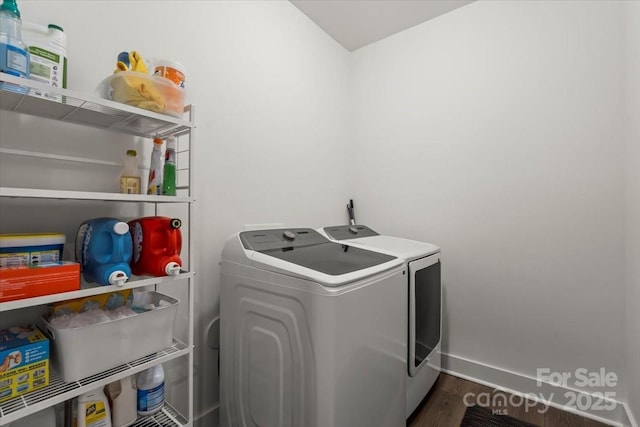 clothes washing area featuring dark wood finished floors, laundry area, baseboards, and separate washer and dryer