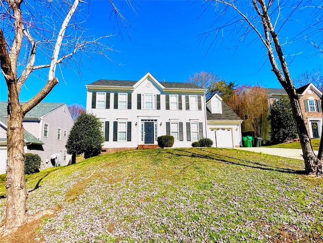 colonial home featuring driveway, a garage, and a front lawn