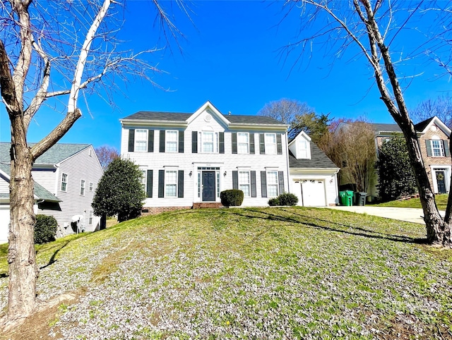 colonial house featuring a front yard, an attached garage, and concrete driveway