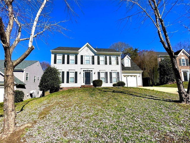 colonial inspired home featuring a garage, concrete driveway, and a front yard