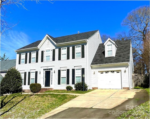 colonial inspired home with driveway, a front yard, and a garage