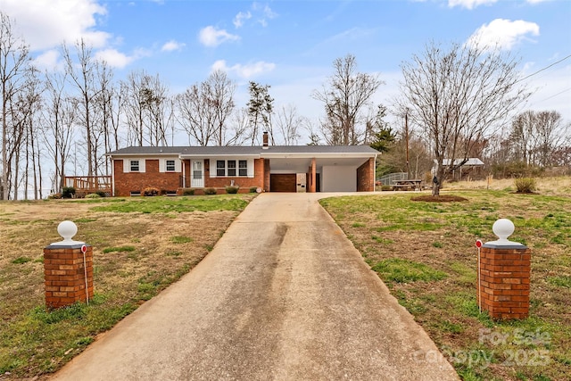 view of front of property with brick siding, a front lawn, concrete driveway, a carport, and a chimney