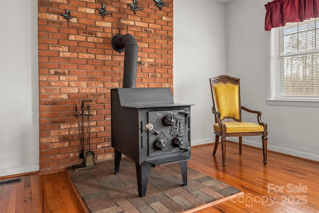 details with visible vents, baseboards, wood finished floors, and a wood stove