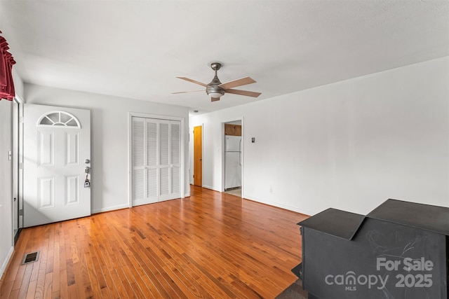 unfurnished living room featuring visible vents, light wood-style flooring, baseboards, and ceiling fan