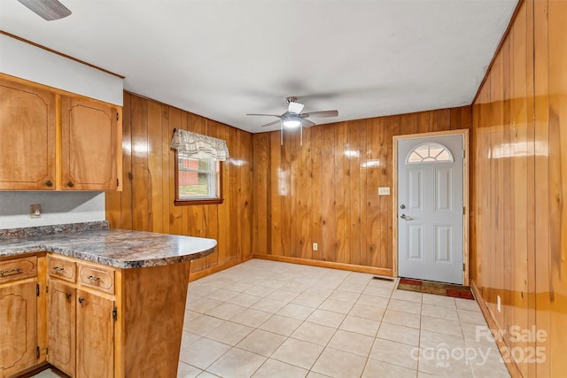 kitchen with brown cabinets, dark countertops, a peninsula, and a ceiling fan