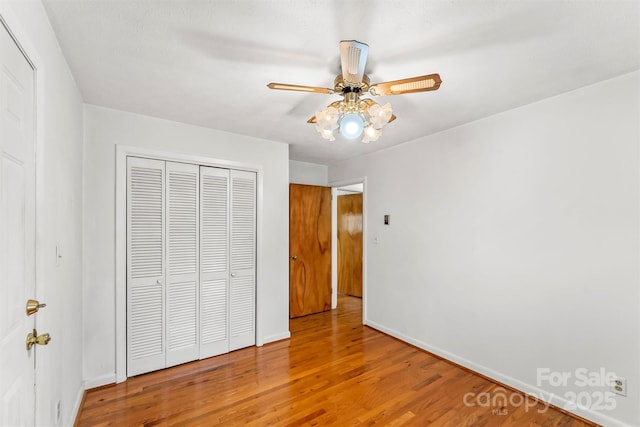 unfurnished bedroom with a closet, baseboards, ceiling fan, and wood finished floors