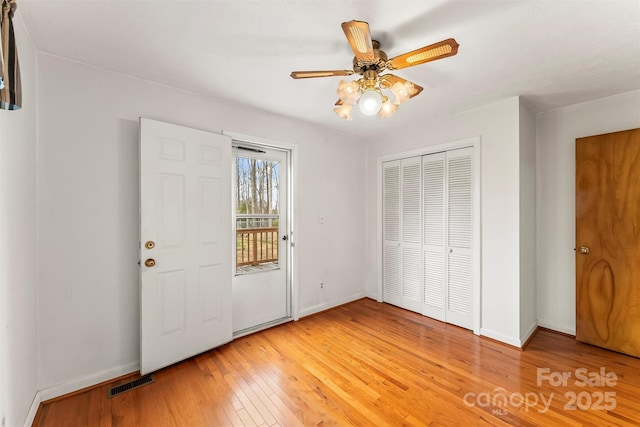 interior space with visible vents, a closet, light wood finished floors, baseboards, and access to exterior