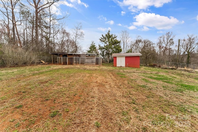 view of yard with a shed, an outdoor structure, and fence