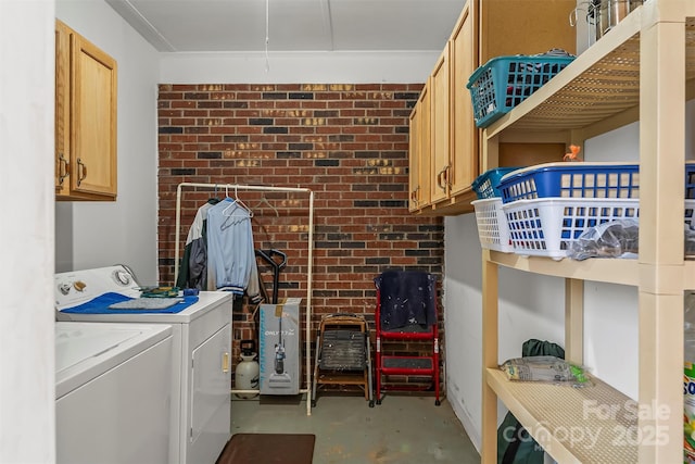 clothes washing area featuring cabinet space, independent washer and dryer, and brick wall